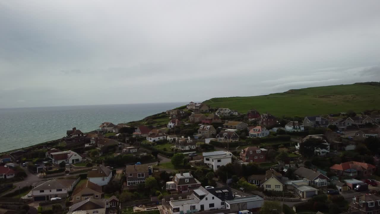 Drone video over residential homes on the sea side cliffs of West Bay, Dorset. Grass fields behind and the sea to the right.