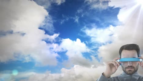 caucasian man wearing vr goggles against spot of light and clouds in the sky