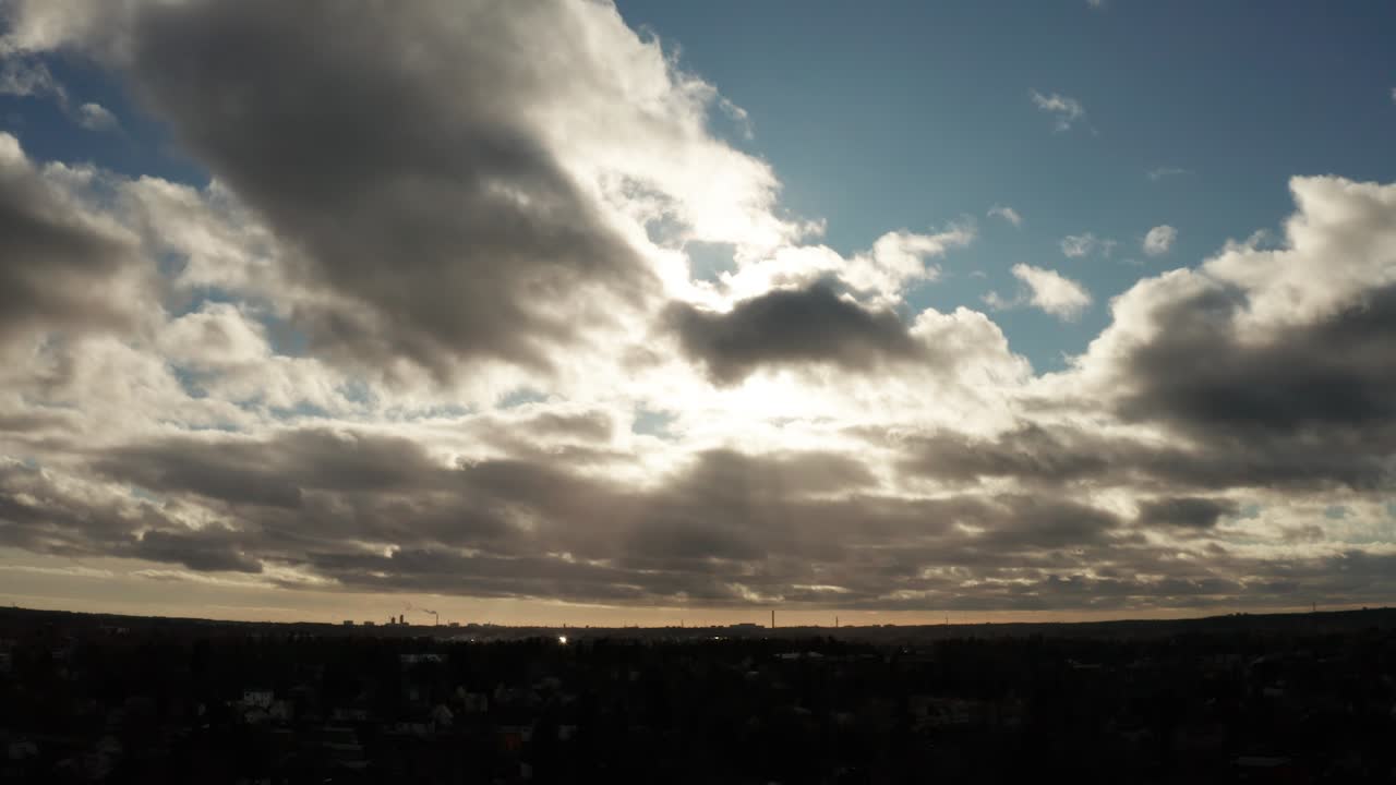 Drone shot of impressive blue cloudy sky with dramatic sunlight, over a city
