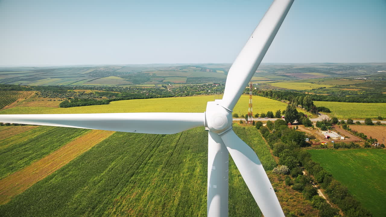 Vista aerea da drone di una turbina eolica funzionante in Moldova. Ampi campi circostanti, villaggio sullo sfondo