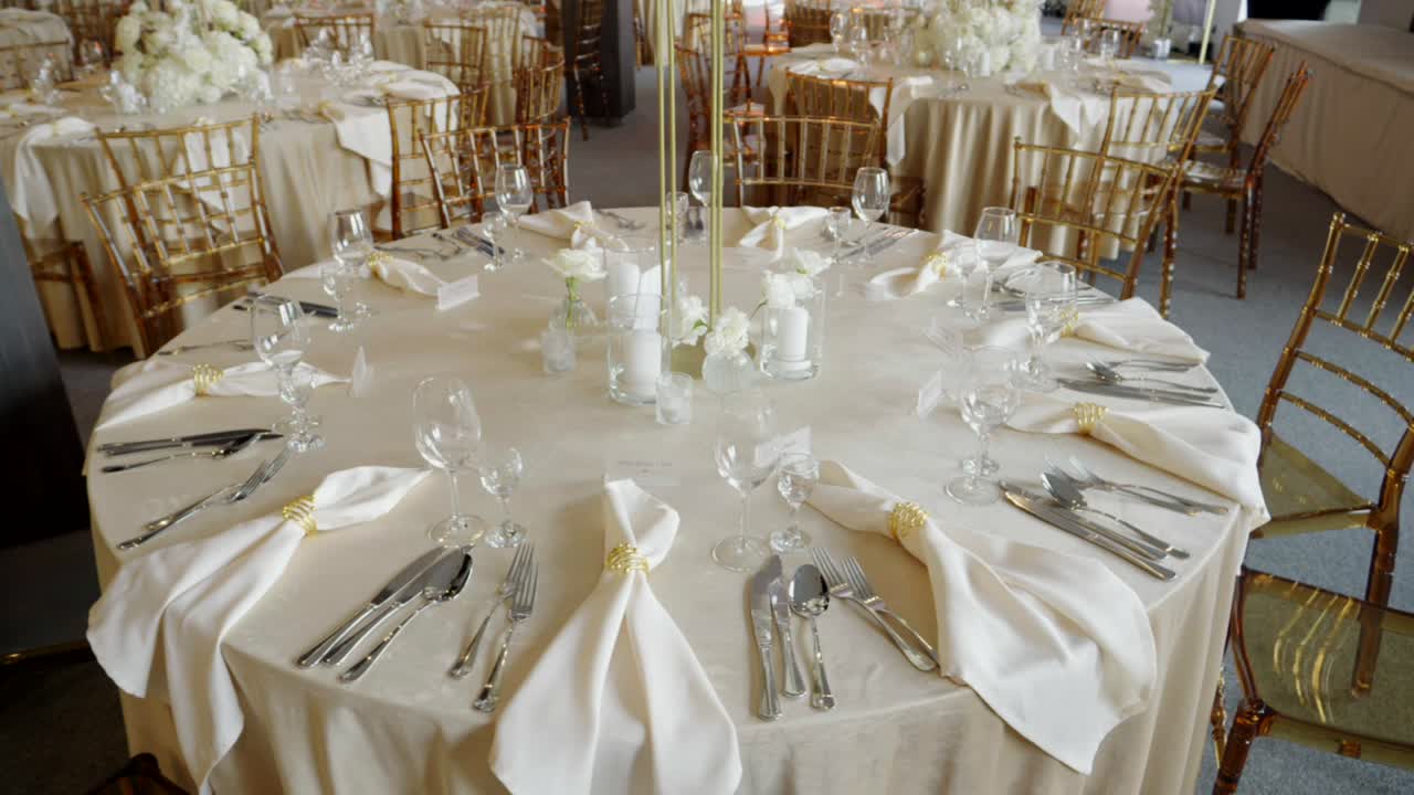 Beautifully decorated elegant round tables, with cutlery and dinnerware laid out.