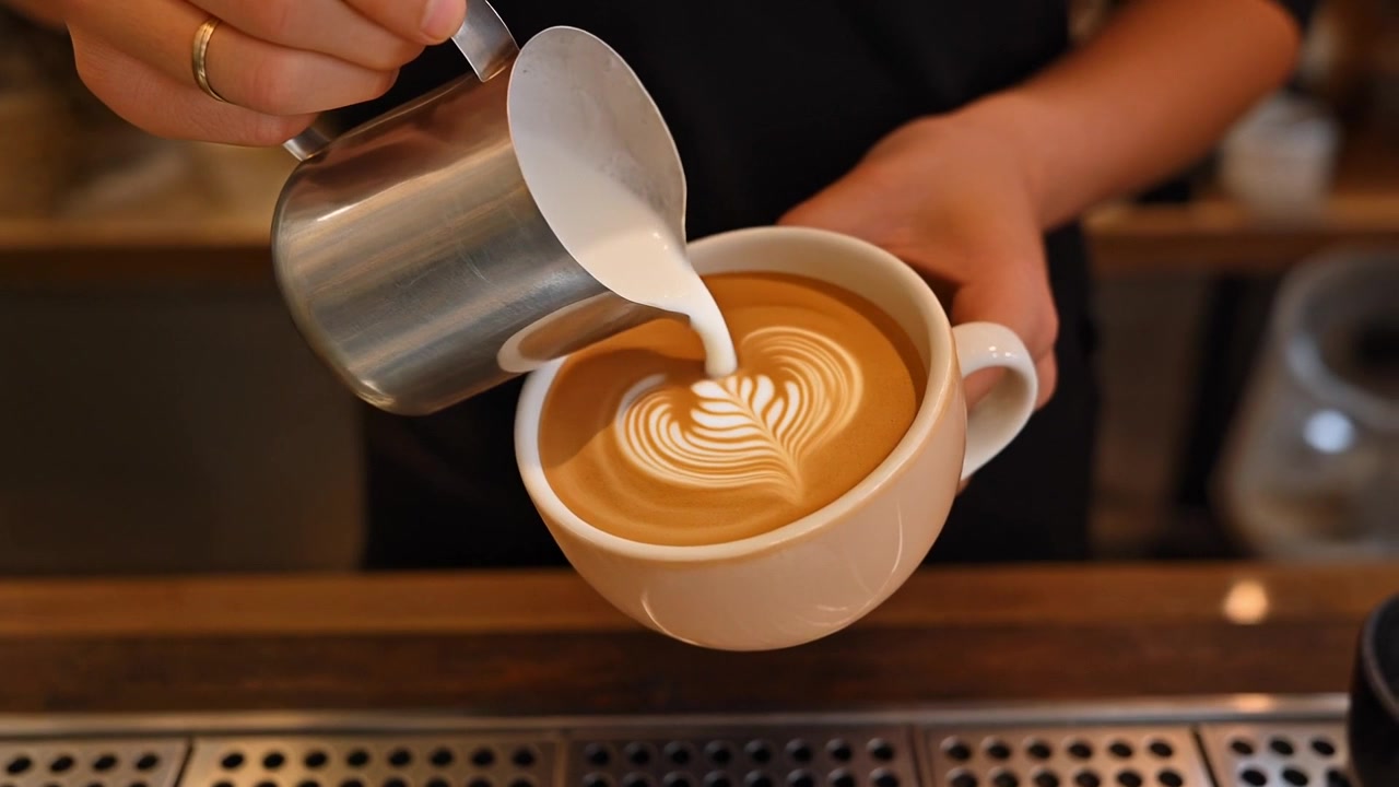 Barista che versa latte montato a vapore per creare latte art in una caffetteria