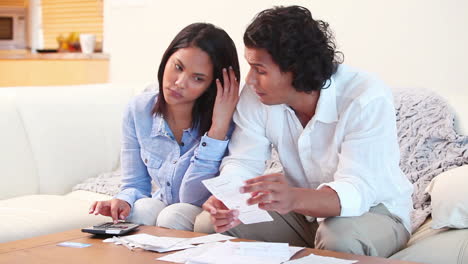 Pareja-En-El-Sofá-Calculando-Sus-Gastos