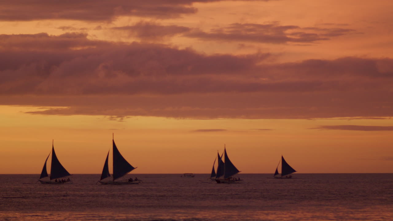 toma panorámica lenta de la playa de boracay con veleros durante la puesta de sol