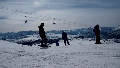 snow boarder starting to move at ski resort on snow covered mountain with chairlift in background