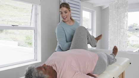caucasian female physiotherapist checking leg of senior woman, copy space, slow motion