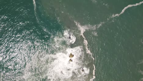 vista vertical hacia abajo de la hermosa agua de mar chocando contra las rocas en nazare, portugal