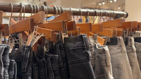 close up rack of jeans clipped on hangers on display in store, clearance sale