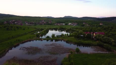 Toma-Aérea-Amplia-De-Un-Lago-De-Pesca-Cerca-De-Un-Pequeño-Pueblo,-Transilvania,-Rumania