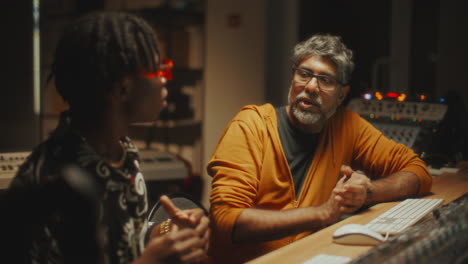 black musician and sound engineer working together in recording studio