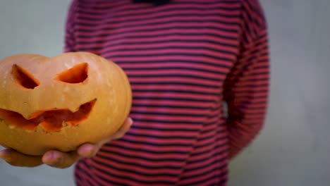 mano sosteniendo calabaza malvada con sonrisa y ojos cortados, artesanías y preparaciones para halloween