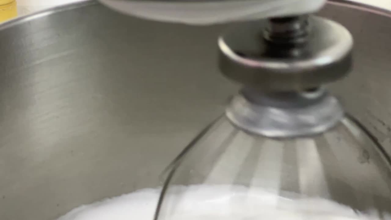 Extreme close up shot of fluffy and soft Swiss meringue buttercream pastry making in progress, electric mixer mixing and beating egg white and sugar until it is glossy peak and stiff peak