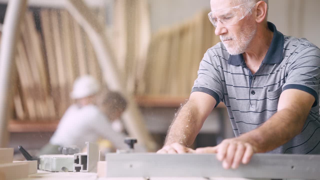 Senior Carpenter Cutting Wood with Saw in Workshop
