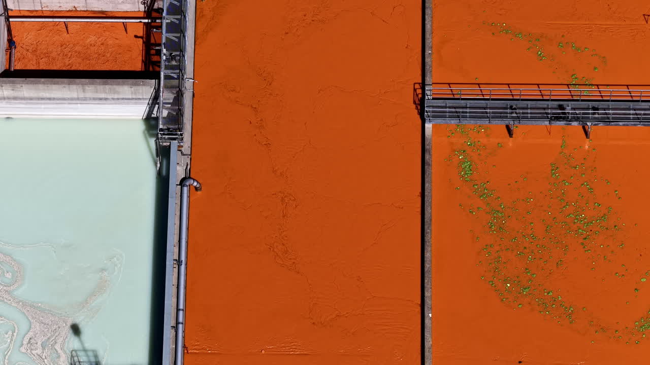 Aerial topdown of oily slick white and orange mix in large wastewater processing tank