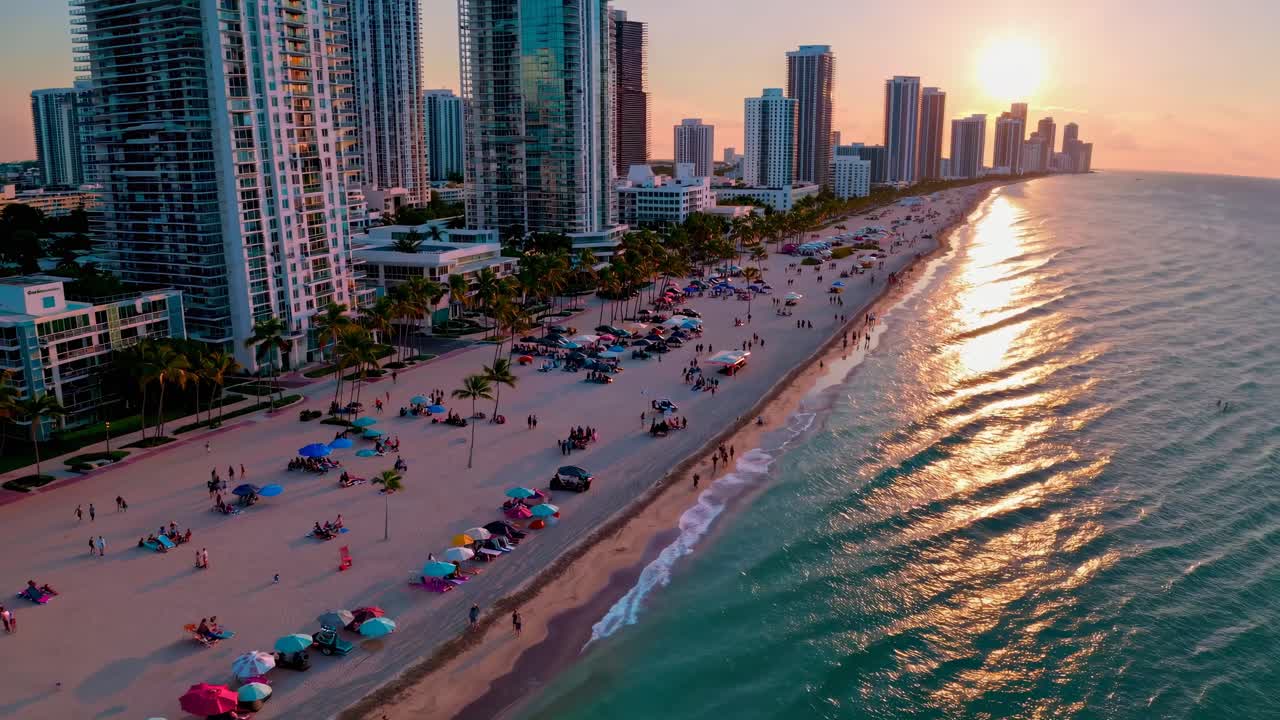 Video aereo che cattura un vivace paesaggio urbano costiero al tramonto, con grattacieli e palme.