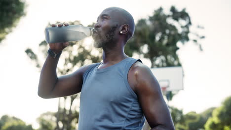 man drinking water after exercise on a basketball court