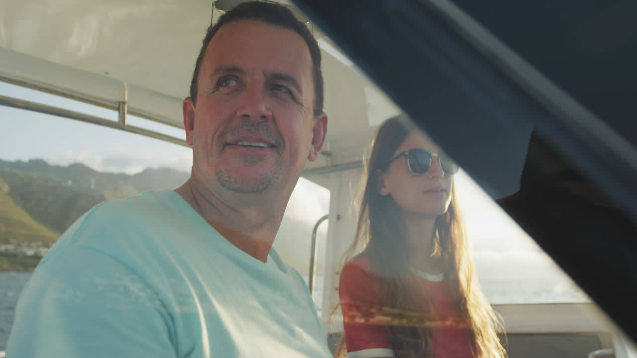 vista lateral de un hombre caucásico y su hija adolescente disfrutando del tiempo juntos en un barco