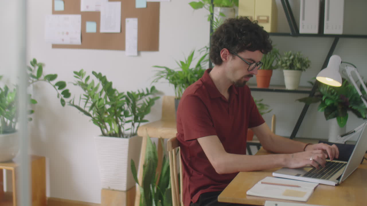 Man Typing on Laptop at Desk in Office