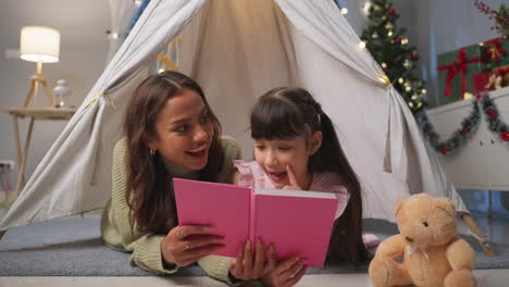 mother and daughter reading in a play tent