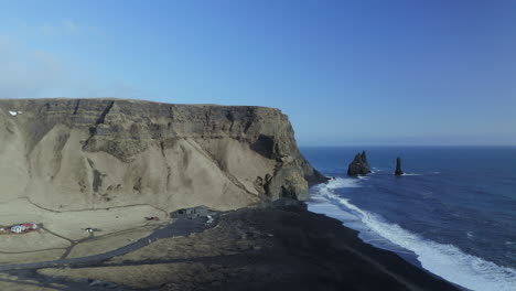 escarpados acantilados con reynisdrangar pilas de mar de basalto en las olas del mar de la playa de reynisfjara cerca de vik en el sur de islandia