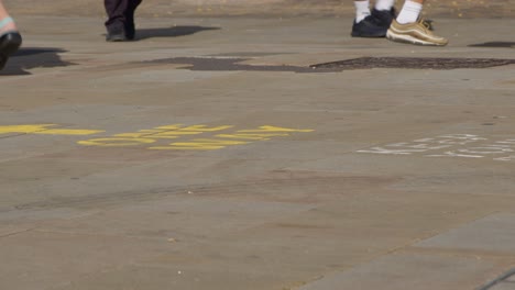 Close-Up-Shot-of-Feet-Walking-Over-One-Way-Pavement-Marking-In-Oxford