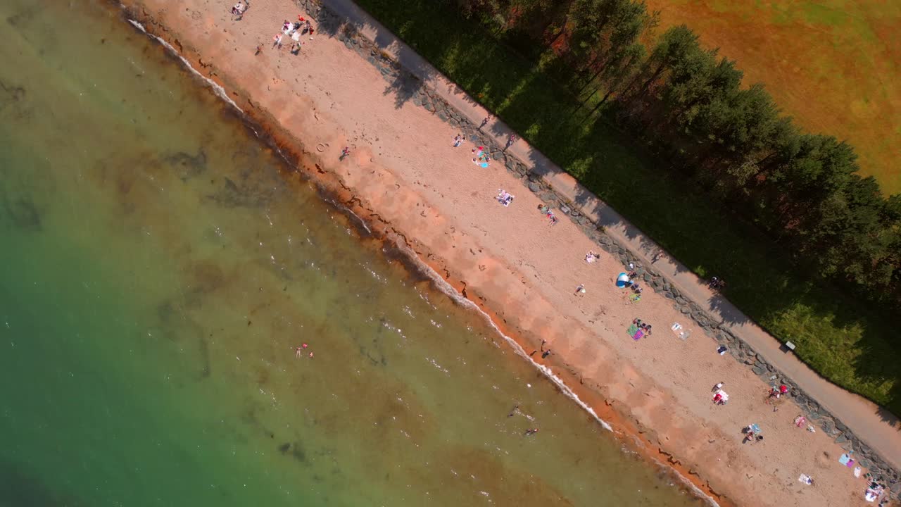Tight rising overhead aerial video of Helen's Bay beach in County Down, Northern Ireland, UK on a bright summer day. Filmed in 4K, 60FPS and with Rec709 color