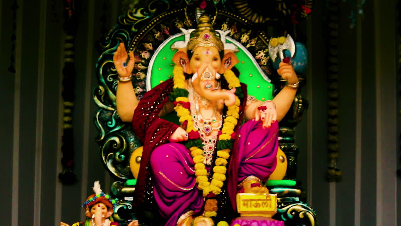 Vibrant Ganesh idol decorated with garlands, jewelry and flowers during Ganesh Chaturthi celebration. Perfect footage for Indian festival, devotion, spirituality and culture themes