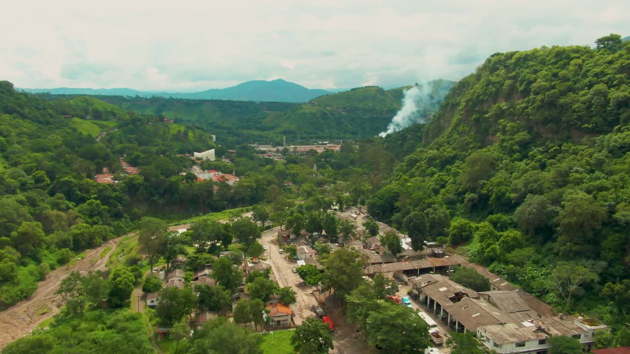 Drone view of town of Atenquique, Jalisco, with a factory with white smoke visible in background