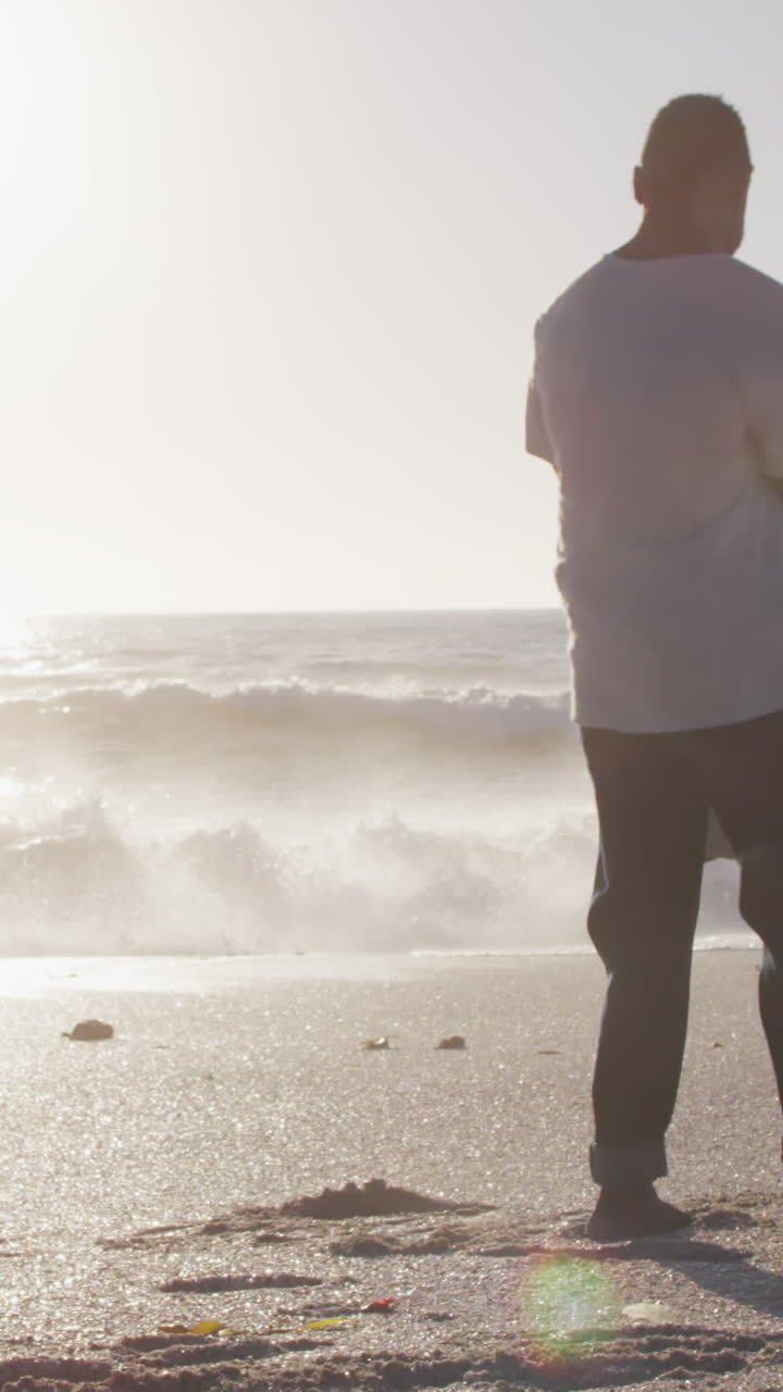 sonriente familia afroamericana cogida de las manos y jugando en una playa soleada