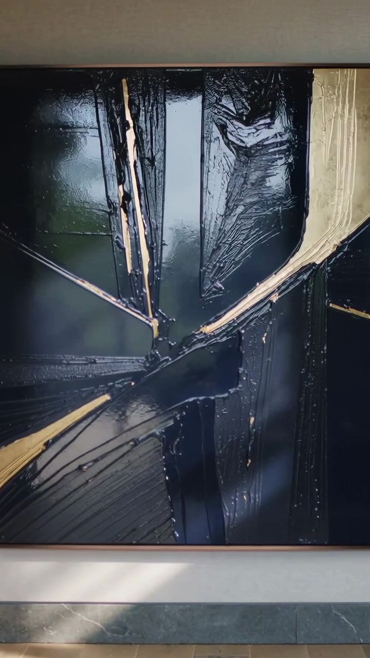 Vertical video: Tilting camera revealing painting at home, showing window light and gold strokes