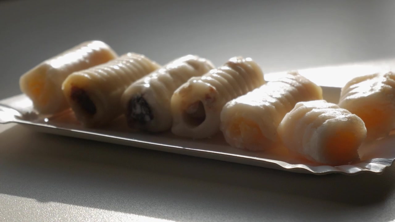 Un vassoio di pasticcini con diverse farciture è illuminato da una luce naturale soffusa su un tavolo