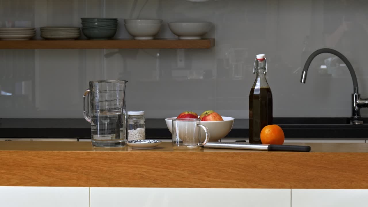 Arrangement of ingredients and cookware for apple beverage on top of kitchen counter