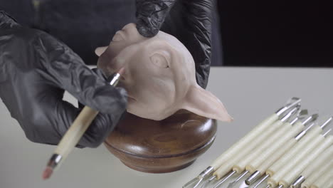 artist finishes the nose of a plasticine puppet head with a modeling tool 4k