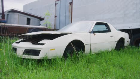 1980s camaro sitting in a field of lush green grass rusting away