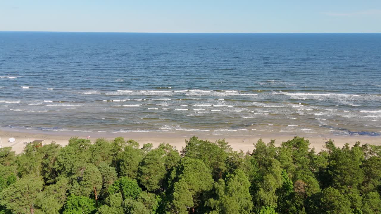 Aerial view over green forest reveals Jurmala’s sandy beach and Baltic Sea waves in Latvia