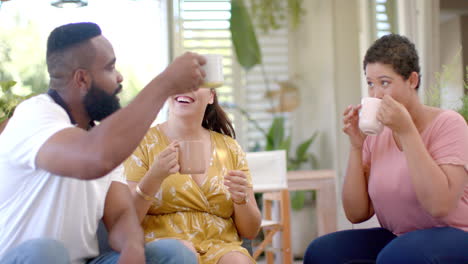 diverse friends toasting with coffee mugs, enjoying time together at home