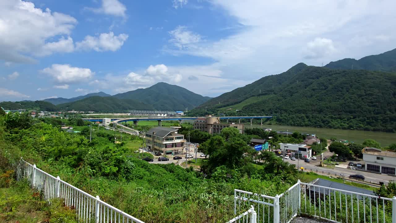 Immersive walking shot glides through a beautiful hillside cafe terrace to reveal a picturesque mountain landscape of the New Cheongpyeong Bridge over the Bukhangang River in Gapyeong