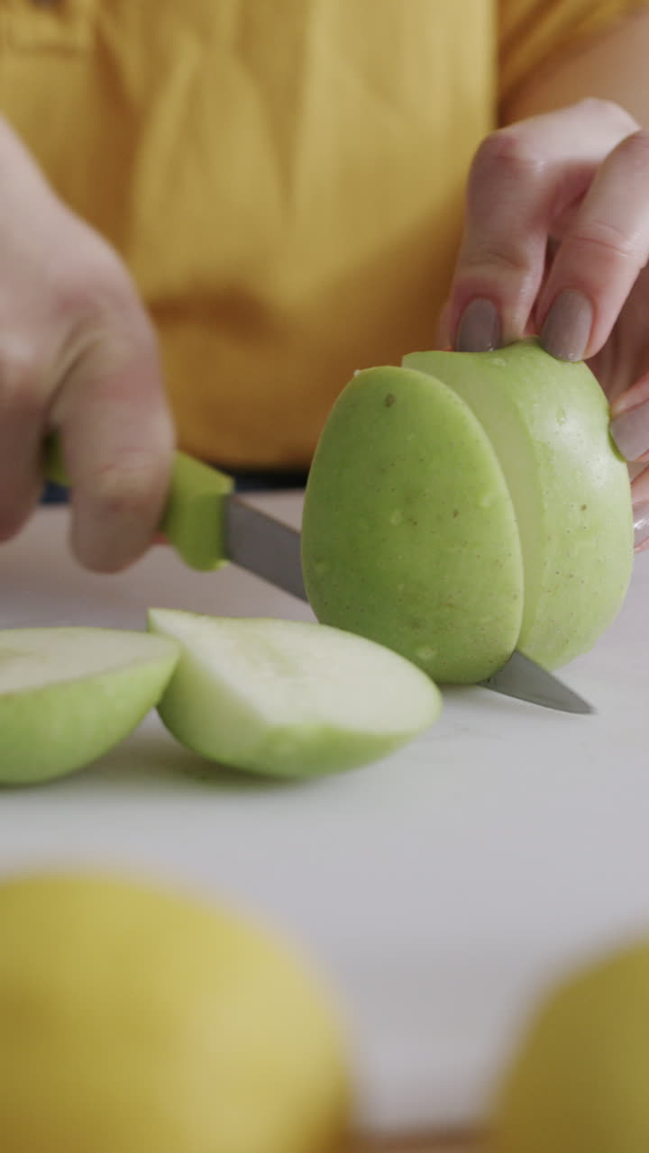 Primo piano di mani che affettano una mela verde fresca su un tagliere