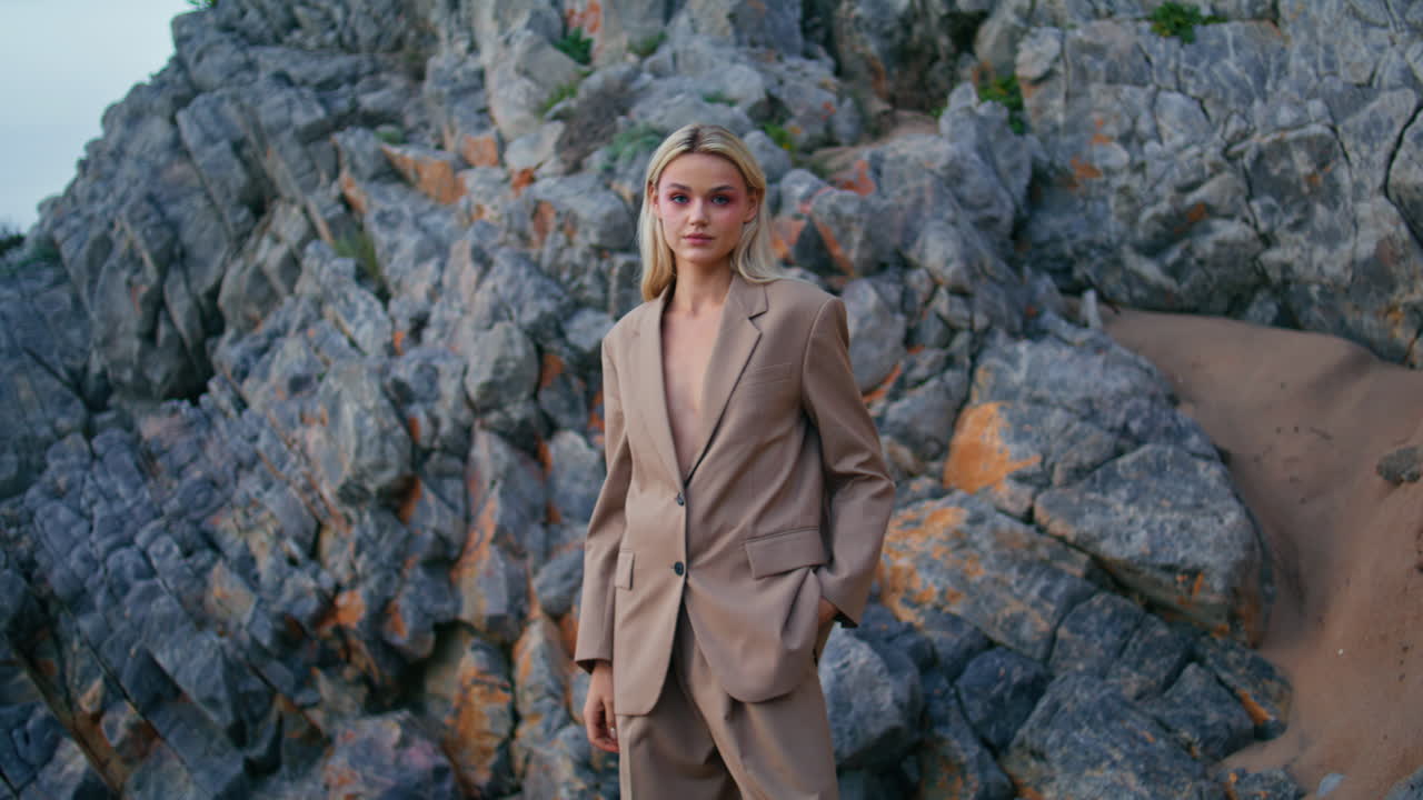 패션 모델 촬영 해변에 우아한 슈트. 섹시한 금발 카메라를 바에 보십시오