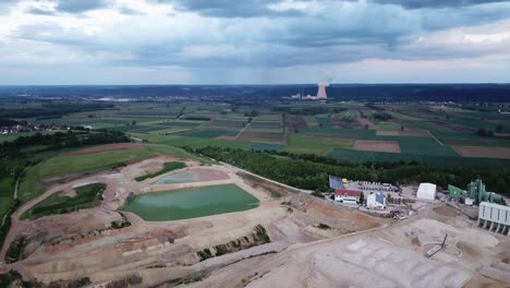 Gravel-pit-against-nuclear-power-plantain-on-the-horizon,-Essenbach,-Bavaria,-Germany