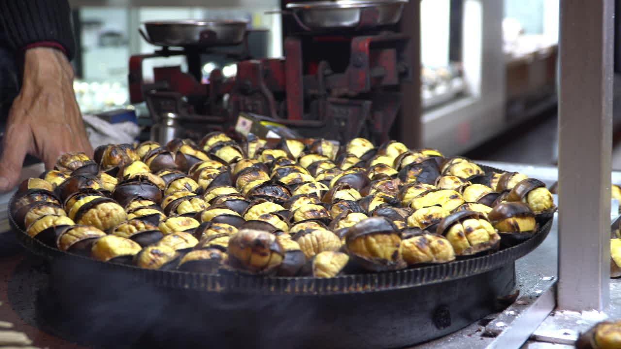Closeup of Old Hand Putting Roasted Chestnuts on Plate in Istanbul