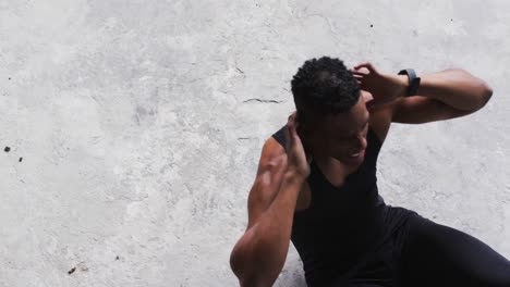 african american man doing crunches on the floor in an empty urban building