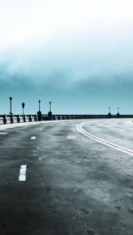 empty road leading through a bridge on a cloudy day