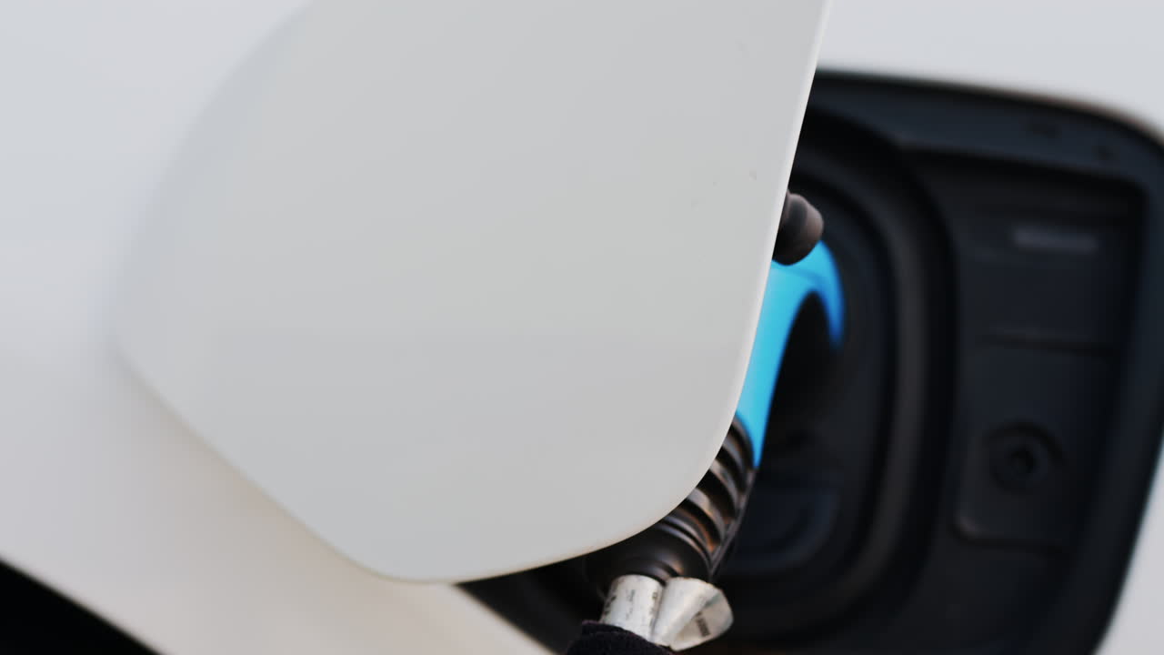 Close up of a blue electric car charger plugged into a white car