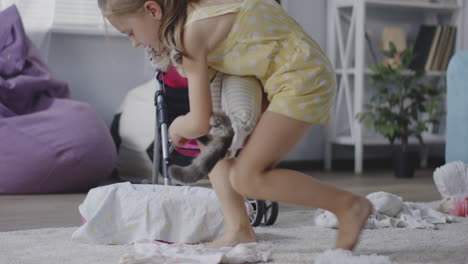 little girl playing with doll and cat