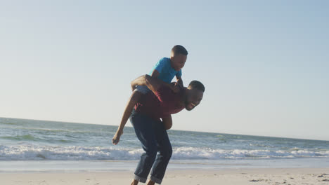 video de un padre y un hijo afroamericanos felices divirtiéndose en la playa