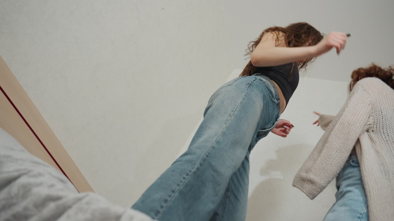 Low Angle Of White Friends Dancing In Small Apartment Room, Energetic Rehearsal Vibe With Denim And Crop Tops, Playful Gestures And Expressive Movement, Creator Practice For Social Content, Candid