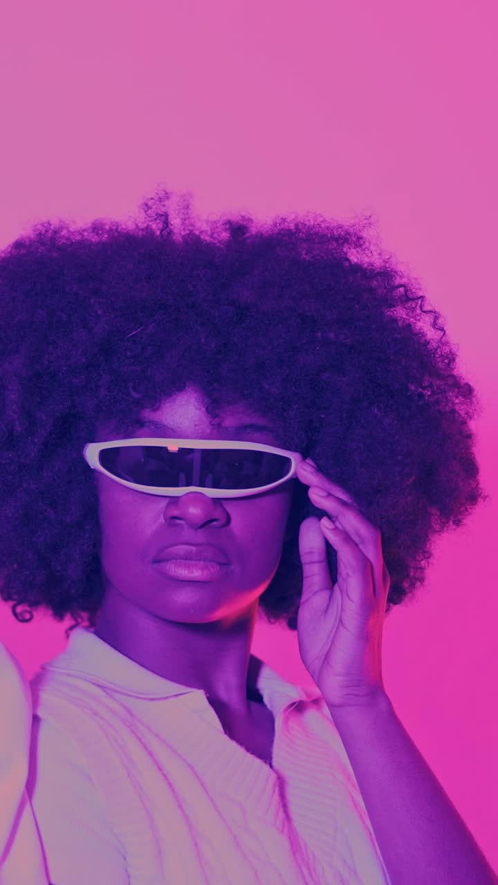 Woman in Futuristic Visor Sunglasses with Afro Hair in Neon Pink Light