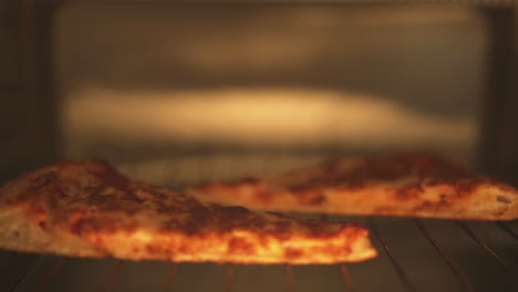 dolly detrás de porciones de pizza calentándose dentro de un horno tostador.