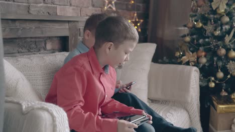 schoolboy-sits-on-couch-holds-tablet-and-speaks-to-brother